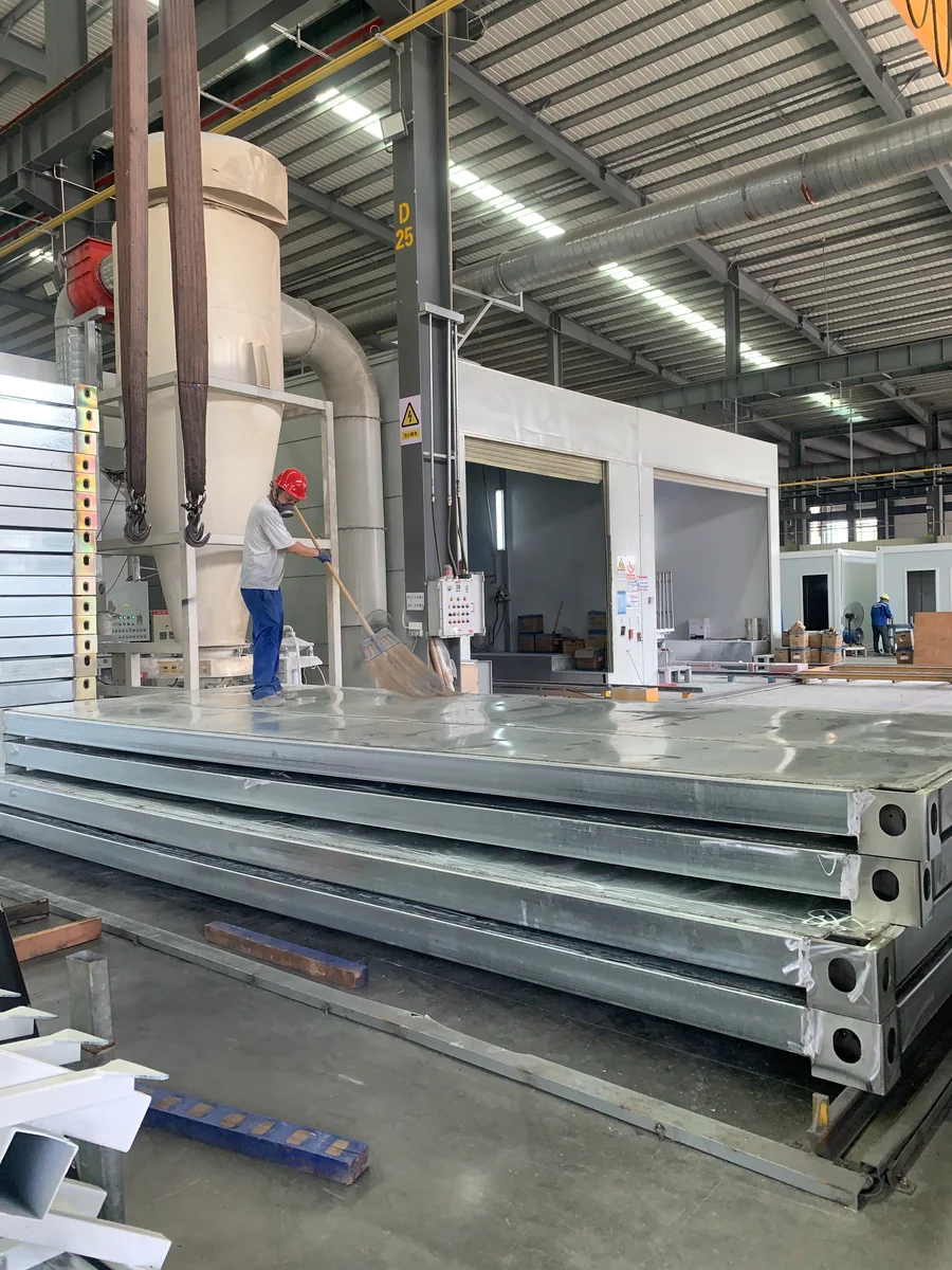 A worker cleaning a steel frame near the factory finishing area